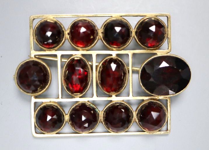 An early 20th century German jugendstil 585 yellow metal and facetted garnet set brooch,